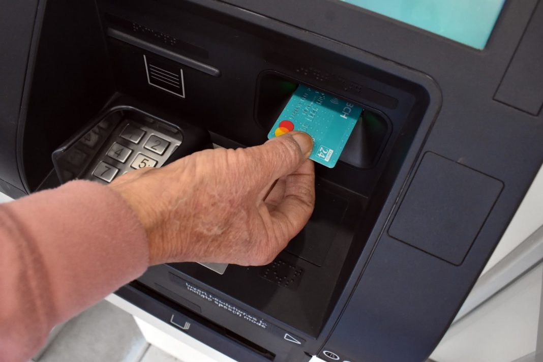 Persona retira una tarjeta de un cajero automático