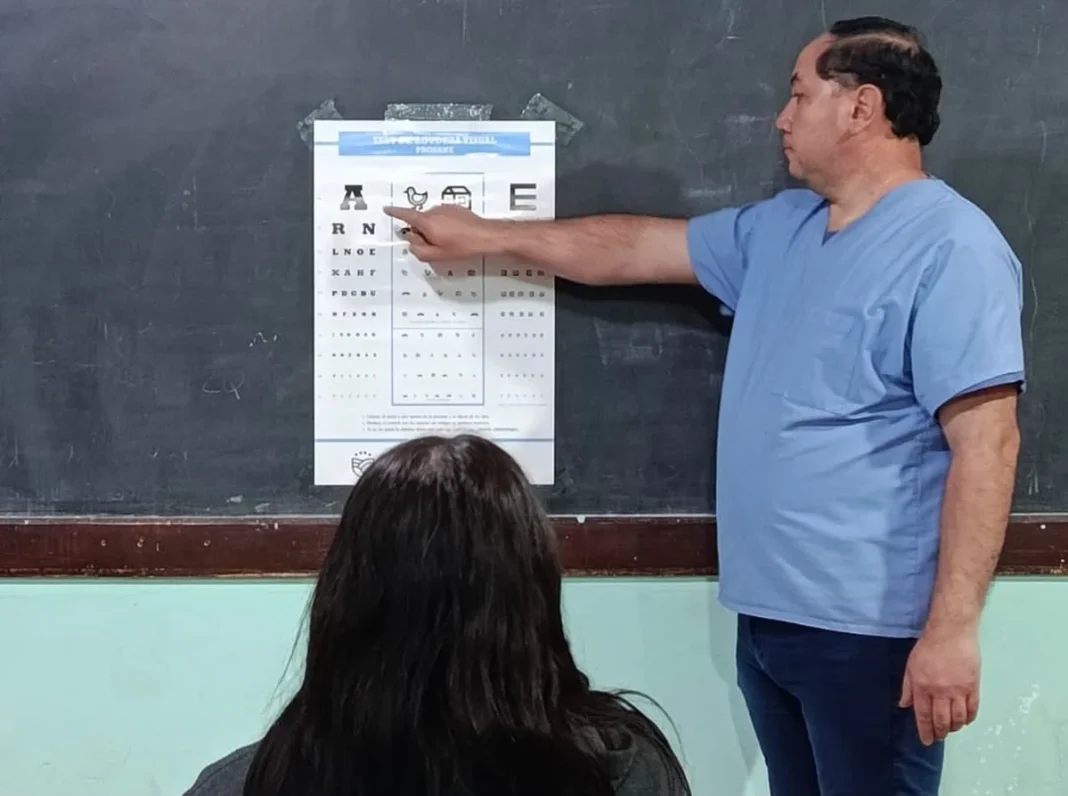 Profesional realiza un control oftalmológico a una estudiante en una escuela
