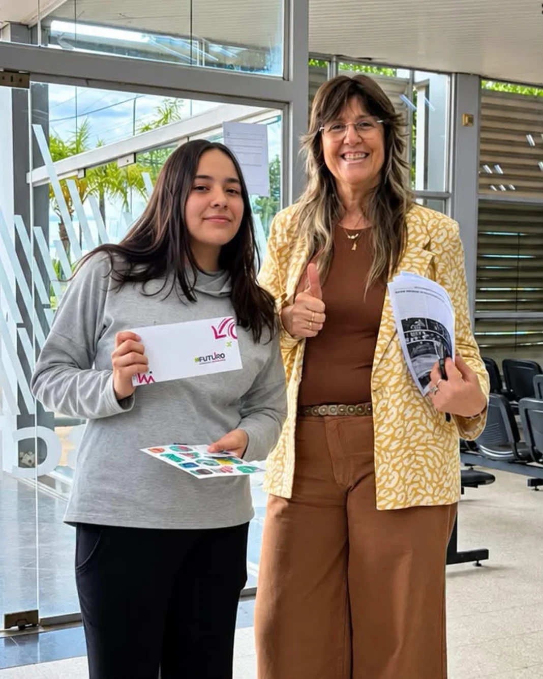 Una estudiante y una mujer muestran materiales del programa +Futuro.