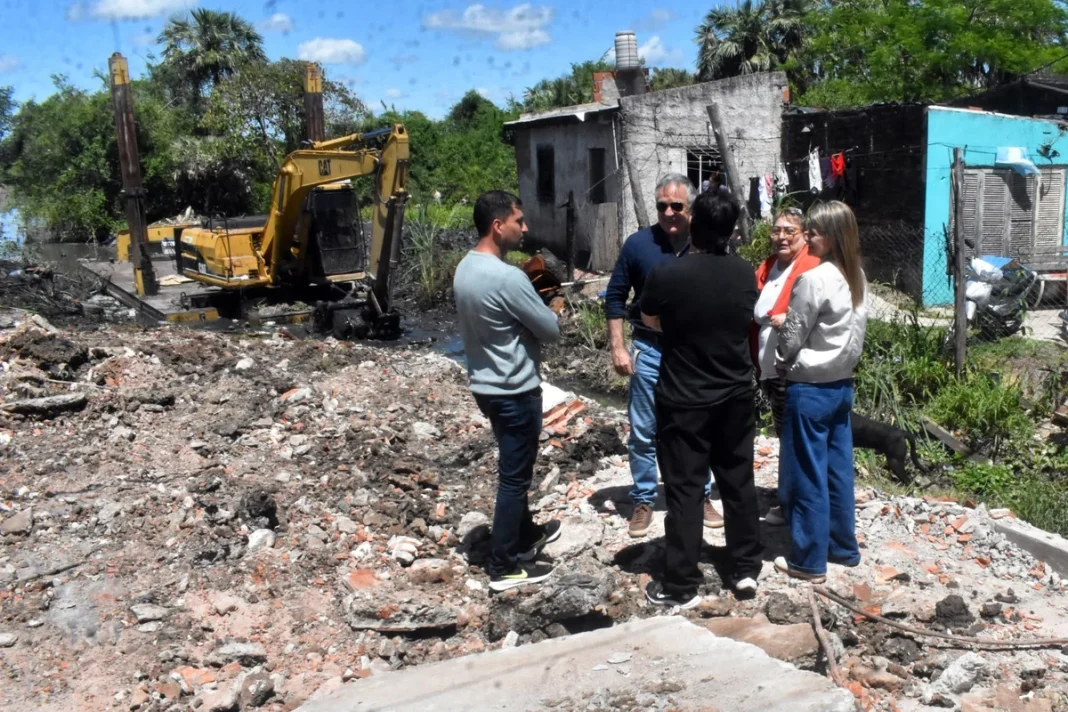 Un grupo de personas observa los trabajos de limpieza con una retroexcavadora en Puerto Vilelas.