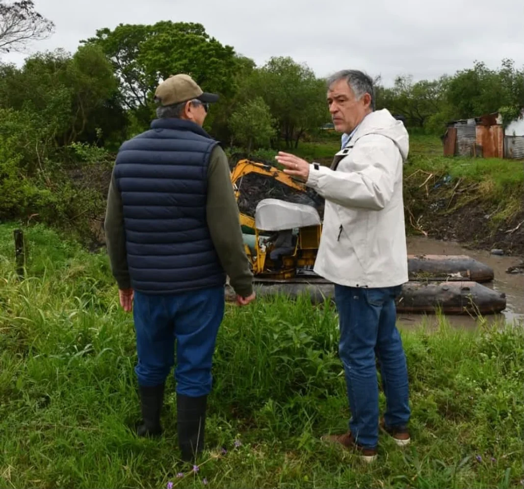 Dos personas observan los trabajos de limpieza del riacho Arazá junto a una máquina